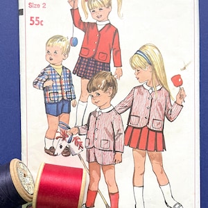 May include: Vintage Simplicity sewing pattern number 6989 for a toddler size 2. The pattern is for a red and white striped jacket and skirt, a plaid jacket and shorts, and a red jacket and skirt. The pattern is priced at 55 cents.