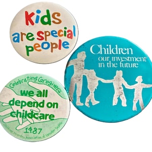 May include: Three vintage pinback buttons with text. One button reads "Kids are special people" in colorful letters. Another says "Children our investment in the future" with a graphic of people. The third button says "Celebrating Caregivers we all depend on childcare".