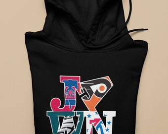 May include: Black hooded sweatshirt with a graphic design of the letters "J-X-W-N" made up of logos from Philadelphia sports teams. The text "(IT'S A PHILLY THING)" is below the graphic.