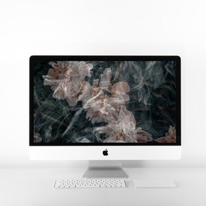 May include: A white desktop computer with a black screen displaying a floral wallpaper. The wallpaper features pink flowers with a smoky, abstract design.