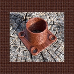 May include: A brown plastic pipe fitting with four screw holes. The fitting is designed to connect two pipes together.