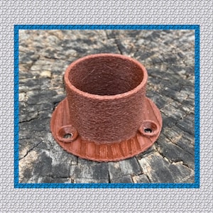 May include: A brown, cylindrical object with a flared base and two holes. The object has a textured surface and appears to be made of a composite material. The base is approximately 2 inches in diameter. The object is likely a decorative or functional item.