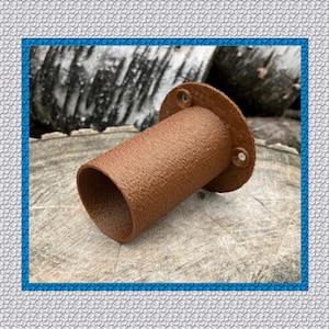 May include: A brown, cylindrical object with a textured surface and a circular flange with three holes. The object is made of a solid material and is set against a natural wood background.