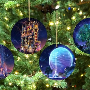 May include: Four round Christmas ornaments with gold string hangers. Each ornament features a different nighttime scene: a castle, a tower, a large tree, and a geodesic sphere. The ornaments are hanging on a Christmas tree.