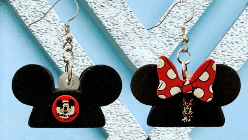 May include: Black Mickey Mouse and Minnie Mouse earrings. The Mickey Mouse earring has a red button with Mickey's face and the words "Always Smile". The Minnie Mouse earring has a red bow with white polka dots.