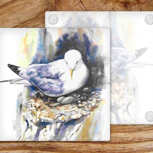 May include: A watercolor painting of a white seagull with purple and blue feathers sitting on a nest made of twigs and branches. The background is a soft watercolor wash of yellow, blue, and gray.