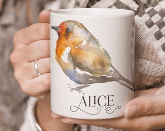 Może przedstawiać: Biały kubek ceramiczny z akwarelą przedstawiającą rudzika. Na kubku widnieje imię "Alice" napisane kursywą pod ptakiem.
