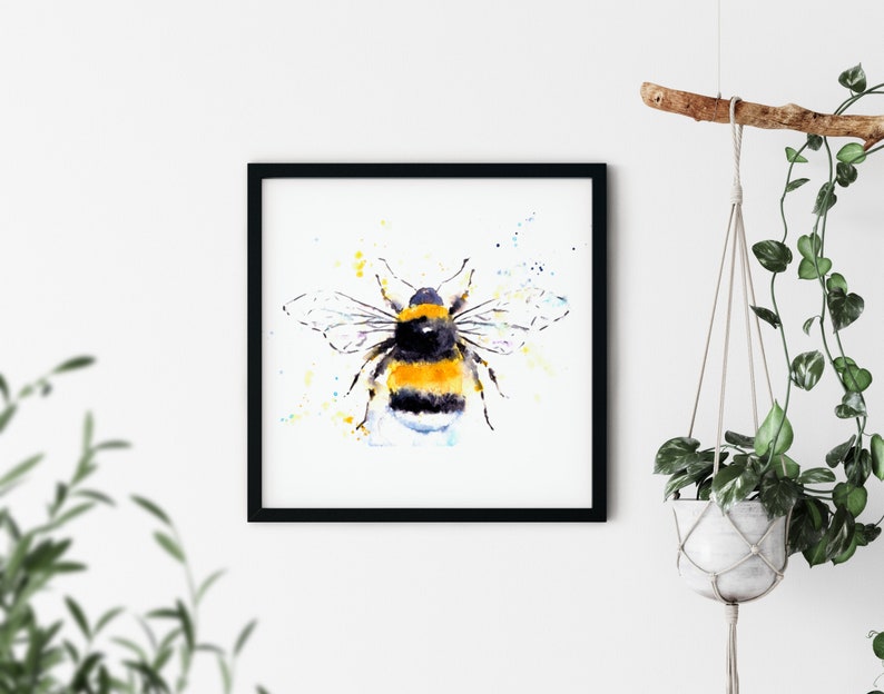 Puede incluir: Una pintura de acuarela de un abejorro con rayas amarillas y negras, rodeado de un fondo de acuarela azul claro y amarillo.