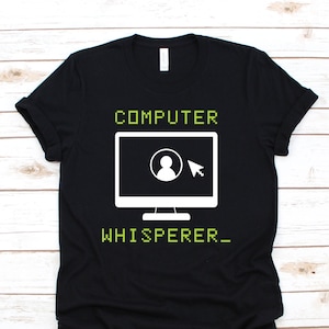 Op de afbeelding: Zwart T-shirt met een witte computerscherm afbeelding en de tekst "COMPUTER WHISPERER_" in groen.