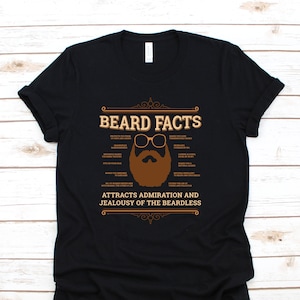May include: Black t-shirt with a brown graphic of a bearded man wearing glasses. The graphic says "Beard Facts" and lists several benefits of having a beard. The text at the bottom says "Attracts admiration and jealousy of the beardless."