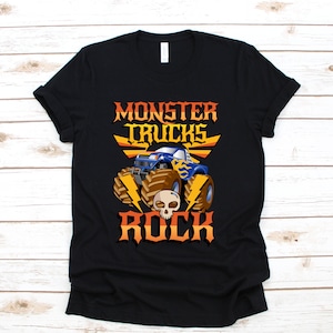 Puede incluir: Camiseta negra con un gr&aacute;fico de un cami&oacute;n monstruo azul con llamas amarillas y el texto "Monster Trucks Rock" en naranja y amarillo.