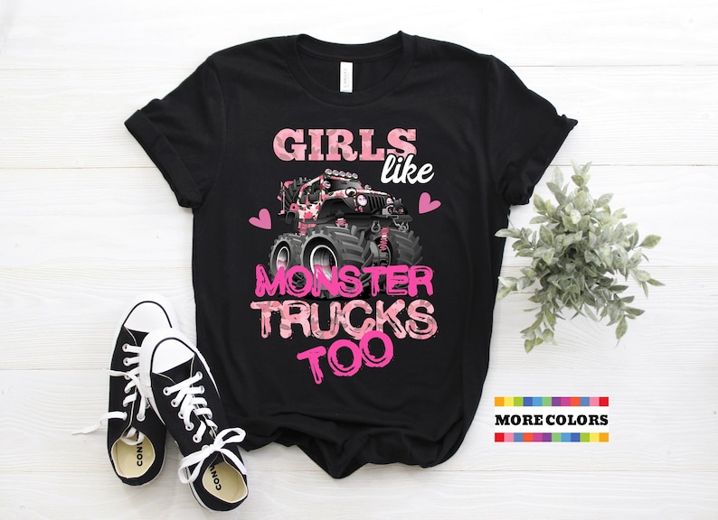 May include: Black t-shirt with a pink camouflage design and the text "Girls like monster trucks too". The design features a pink monster truck with hearts on either side.