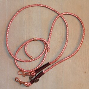 May include: A rose gold leather dog leash with two clips and a braided design.