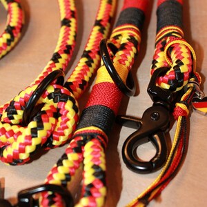 May include: A black, yellow, and red braided rope dog leash with two black metal clips and a small German flag charm.