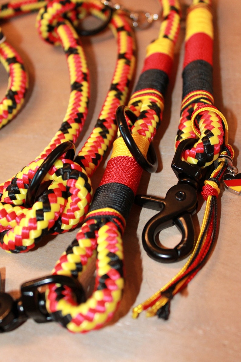 May include: A black, yellow, and red braided rope dog leash with two black metal clips and a small German flag charm.