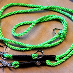 May include: A bright green double dog leash with two metal clips and a metal ring. The leash is made of braided rope and has black accents.