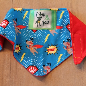 May include: Blue and red dog bandana with a superhero dog print and the text "Filou & You".
