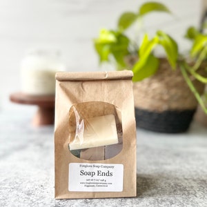May include: A brown paper bag with a window showing soap ends. The bag is labeled "Foxglove Soap Company Soap Ends net wt 7 oz/ 198 g www.foxglovesapcompany.com Higganum, Connecticut"