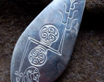 Puede incluir: Un collar con un colgante de plata con un diseño de nudo celta. El colgante tiene forma de lágrima y presenta un árbol y un animal estilizados.