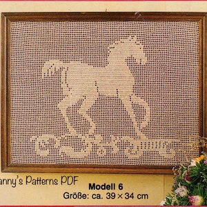 May include: A framed, crocheted artwork featuring a rocking horse design. The artwork is in a wooden frame and measures approximately 15 x 13 inches. The text "Modell 6" is visible in the lower right corner, along with the text "Granny's Patterns PDF".