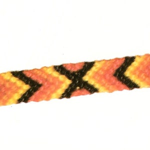 May include: A handmade friendship bracelet with a chevron pattern. The bracelet features orange, yellow, and black threads woven together. The ends of the bracelet are a thinner, patterned design. The bracelet is displayed against a white background.