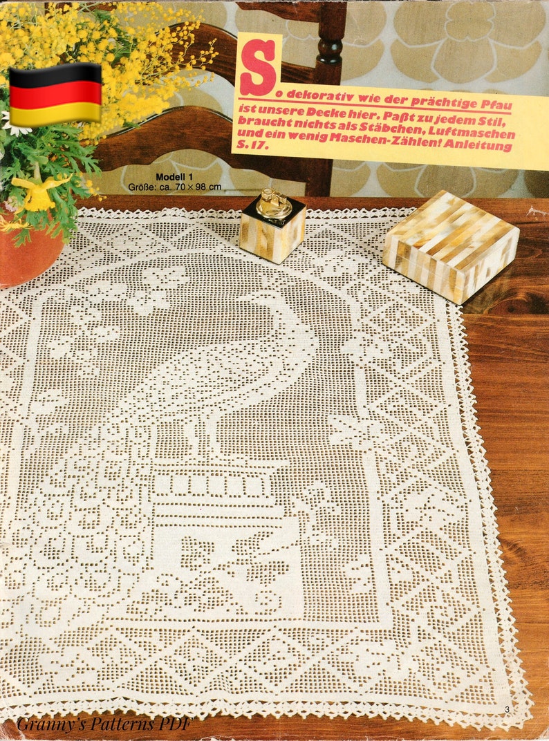 May include: Cream-colored, crocheted peacock tablecloth, approximately 27.5 x 38.5 inches, with a detailed peacock design in the center and a decorative border. The image includes a German flag and text in German.