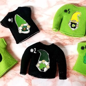 May include: Ten elf-sized St. Patrick's Day shirts and sweaters in green and black with various designs including a gnome, a pot of gold, and a shamrock. The shirts are numbered 1 through 5.
