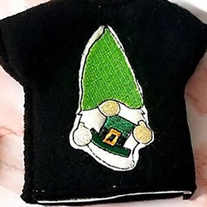 May include: Black t-shirt with an embroidered green gnome wearing a green hat with a gold buckle.