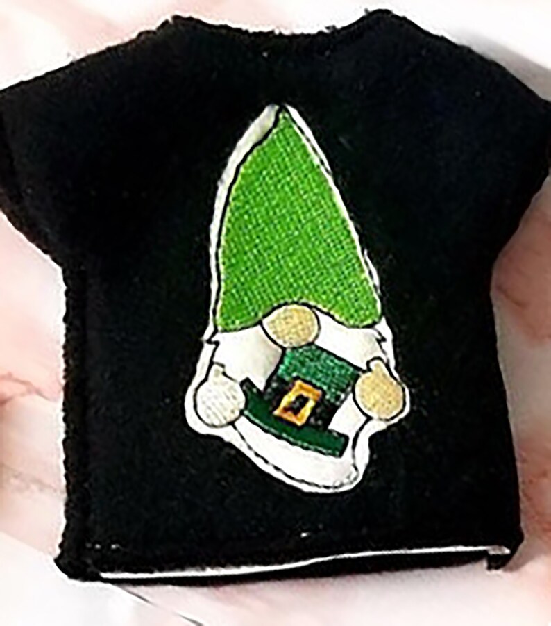 May include: Black t-shirt with an embroidered green gnome wearing a green hat with a gold buckle.