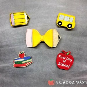 May include: A collection of felt school-themed embellishments, including a yellow pencil, a yellow school bus, a bow shaped like a pencil, a stack of books with an apple, and a red apple with the text "First Day of School".