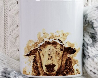 May include: White ceramic mug featuring a sheep design in shades of brown. The sheep's face is the focal point, with a textured, watercolor-like effect. The mug is set against a cozy, knitted background, with the brand logo "BEANY BEANY" visible.
