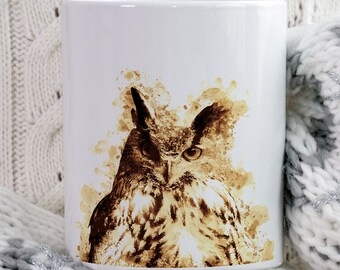 May include: White ceramic mug featuring a watercolor-style owl illustration in shades of brown and tan. The mug is set against a cozy, textured background. The mug has the words "BEANY BEANY" in a brown circle.