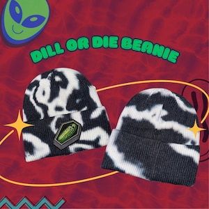 May include: Two black and white tie-dye beanies with the text "DILL OR DIE BEANIE" in green. One beanie has a patch of a pickle in a coffin. The background is red with a green alien and yellow star accents.