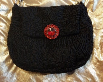 Black, vintage lambskin shoulder bag with adjustable cross-body strap.  Fully lined with red wool. Magnetic snap closure.