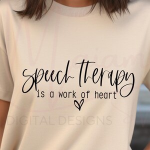 May include: A beige t-shirt with the words "Speech Therapy is a work of heart" in black script. A small heart graphic is below the text. The words "DIGITAL DESIGNS" are printed in a smaller font below the heart.