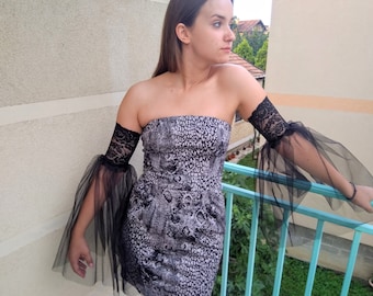 May include: A strapless dress with a black and white snake print pattern. The dress has black tulle sleeves with lace trim.