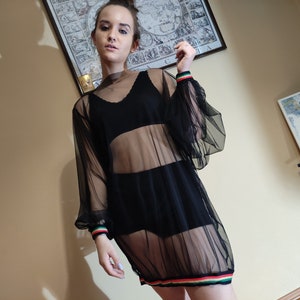 May include: A black sheer mesh dress with long sleeves and a colorful stripe around the bottom hem.