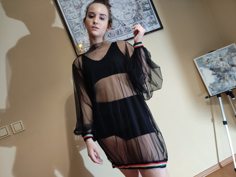 May include: A black sheer mesh dress with long sleeves and a colorful stripe around the bottom hem.