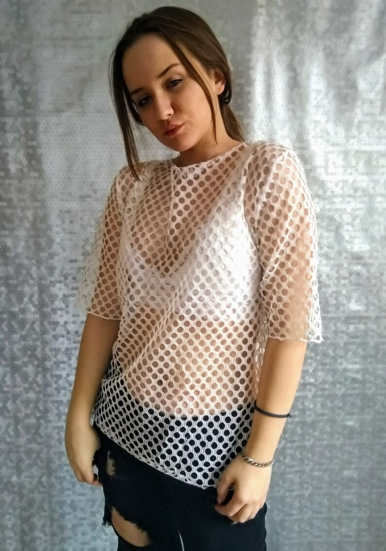 May include: White mesh top with a round pattern. The top is sheer and has short sleeves.