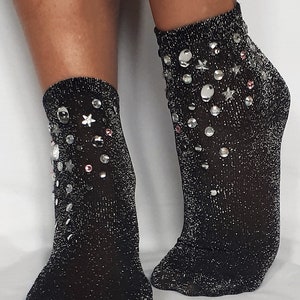 May include: A pair of black sparkly socks with silver and pink embellishments. The socks are ankle-length and have a glittery finish.
