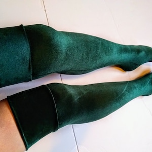 Peut inclure: Une paire de bas hauts de cuisse vert foncé avec une finition satinée.