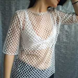 May include: White mesh top with a round pattern. The top is sheer and has a loose fit.