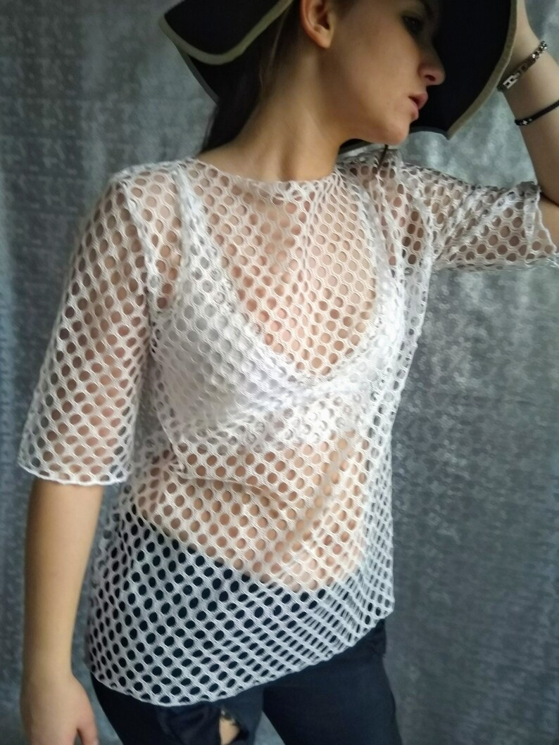 May include: White mesh top with a round pattern. The top is sheer and has a loose fit.