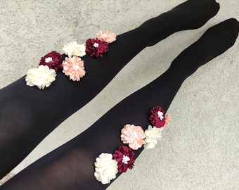 May include: Black tights with pink, white, and burgundy fabric flowers attached to the legs.
