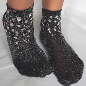 May include: A pair of black ankle socks with silver glitter and rhinestones. The socks have a sparkly, festive look.