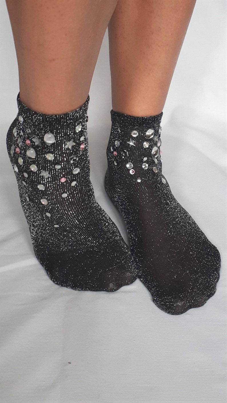 May include: A pair of black ankle socks with silver glitter and rhinestones. The socks have a sparkly, festive look.