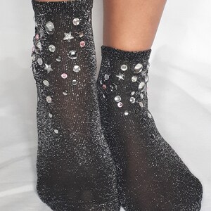 May include: A pair of black sparkly socks with silver glitter and rhinestones in a star and circle pattern.