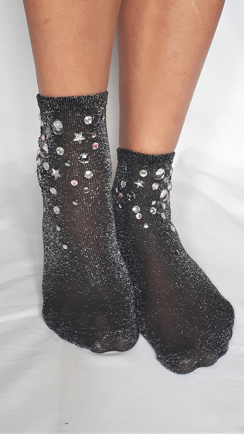 May include: A pair of black sparkly socks with silver glitter and rhinestones in a star and circle pattern.