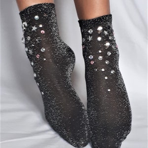 May include: A pair of black sparkly socks with silver and pink rhinestones in a star and circle design.