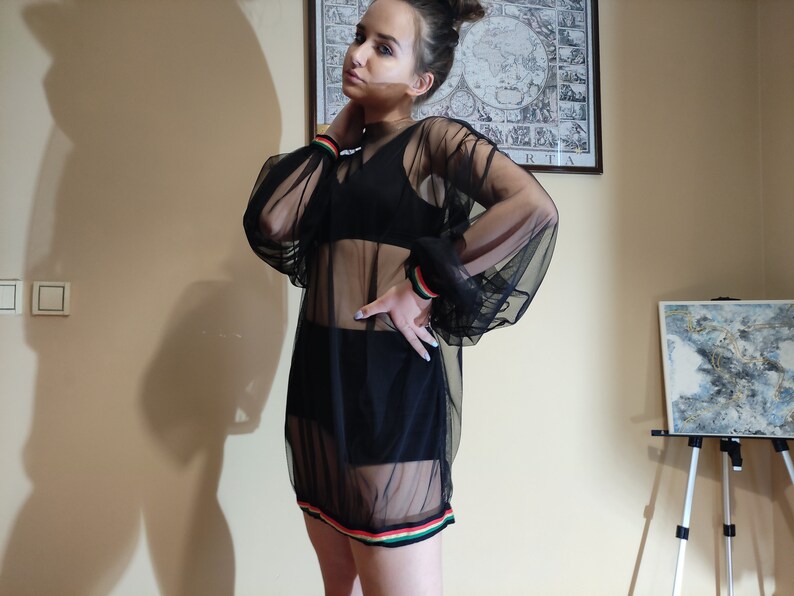 May include: A black sheer dress with long sleeves and a colorful stripe around the hem. The dress is made of a lightweight, breathable fabric and has a relaxed fit.